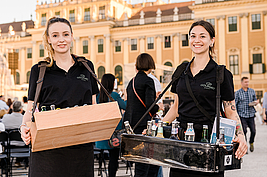 Zwei Mitarbeiterinnen mit Bauchläden die bei einer Veranstaltung vor dem Schloss Schönbrunn posieren